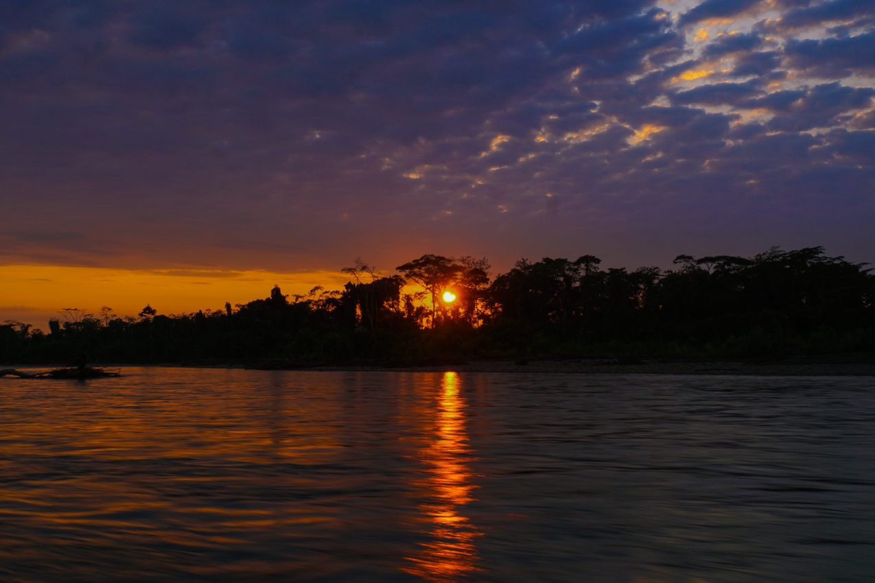 The sun creates beautiful colors as it rises over the Madre de Dios River in the Amazon Rainforest in Peru